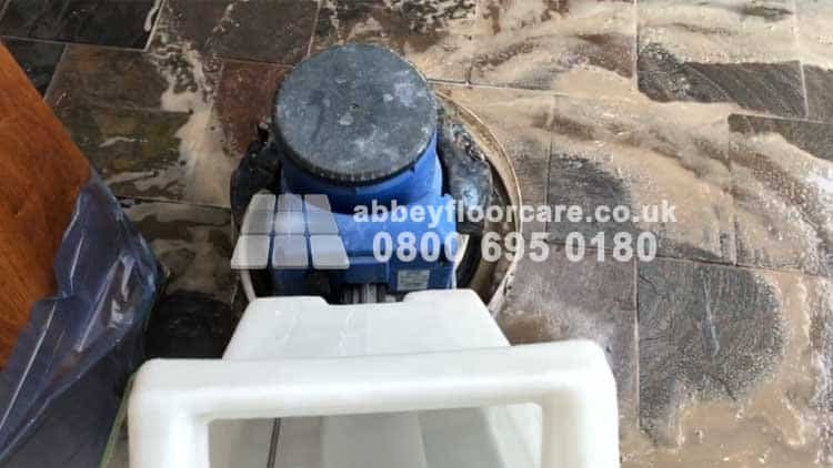 Machine scrubbing a textured slate floor in Barnes during coating removal